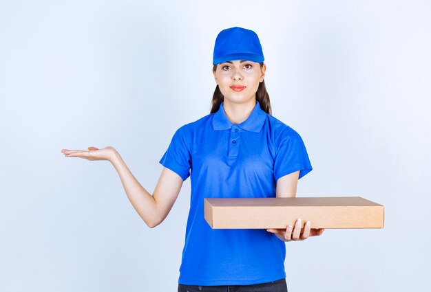 Empleada de entrega en uniforme con caja de papel artesanal.