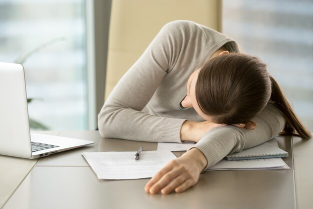 Empleada femenina dormita en el lugar de trabajo en la oficina