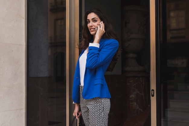 Empleada guapa hablando por teléfono en el vestíbulo