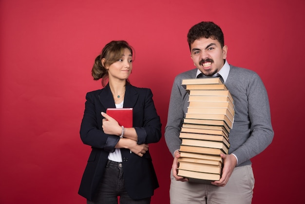 Empleada mirando al hombre con un montón de libros