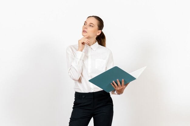 Empleada de oficina en blusa blanca sosteniendo y leyendo archivo azul sobre blanco