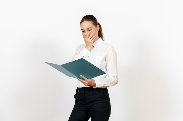 Empleada de oficina en blusa blanca sosteniendo y leyendo archivo azul sobre blanco