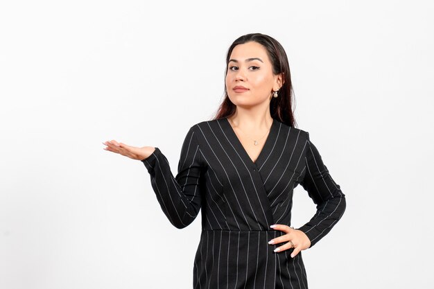 Empleada de oficina en estricto traje negro posando en blanco