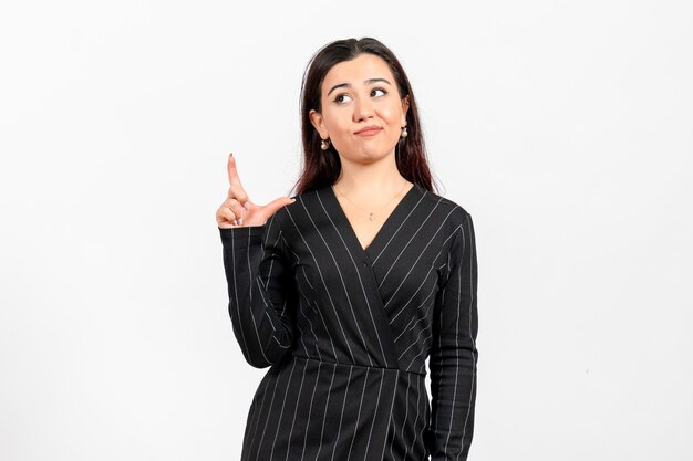 Empleada de oficina en estricto traje negro posando en blanco