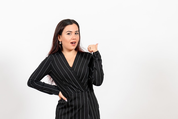 Empleada de oficina en estricto traje negro posando en blanco