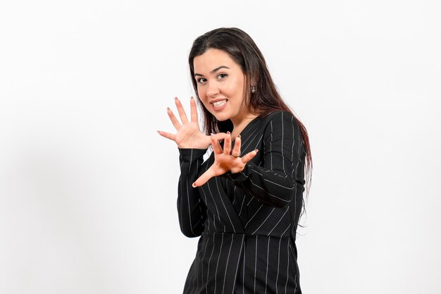 Empleada de oficina en estricto traje negro posando en blanco