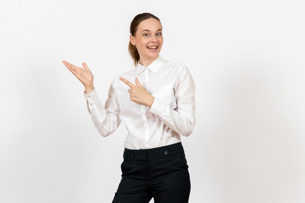 Empleada de oficina posando y sonriendo en blusa blanca sobre blanco