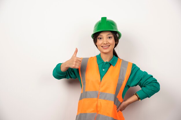 Empleada sonriente con el pulgar hacia arriba sobre fondo blanco.