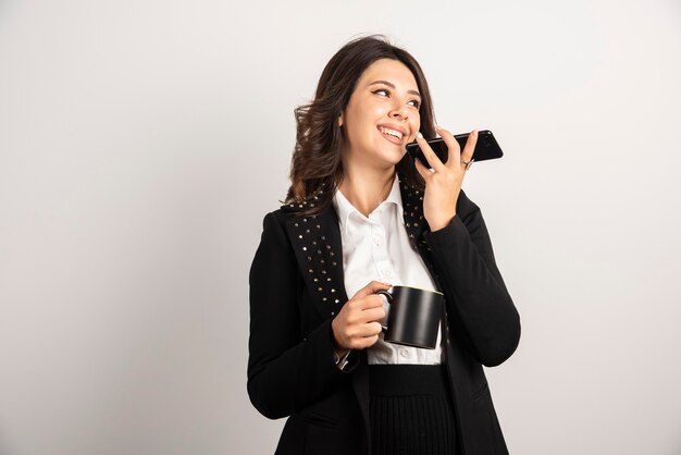 Empleada sosteniendo una taza de té y teléfono