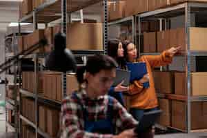 Foto gratuita empleadas asiáticas del almacén comprobando la calidad del embalaje del paquete en la sala de almacenamiento postal. operador de envío de almacén que muestra los productos en stock en los estantes al gerente de logística