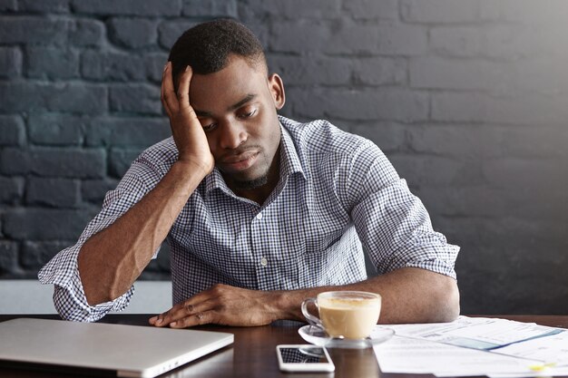 Empleado africano-americano joven cansado frustrado que toca su cabeza