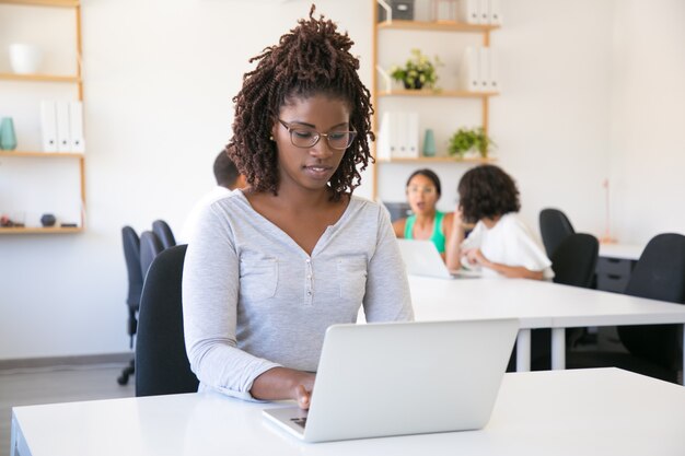 Empleado afroamericano enfocado en positivo trabajando en computadora