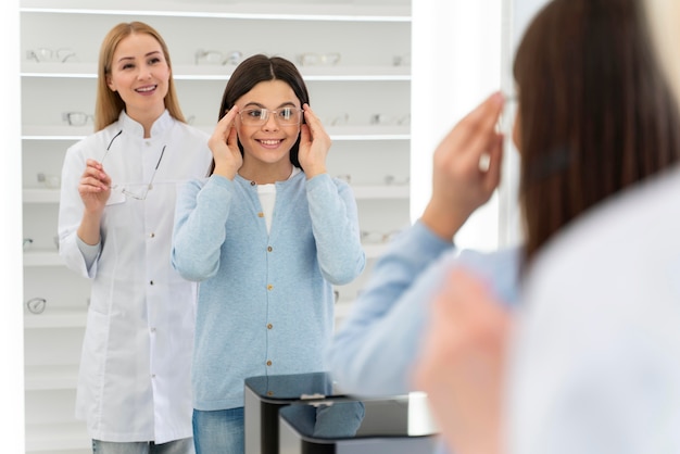 Empleado ayudando a niña a probarse gafas