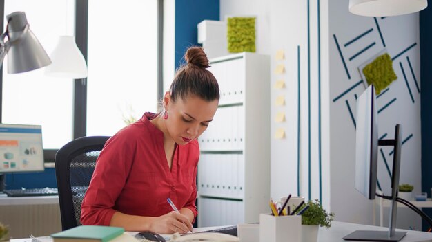 Empleado de la empresa tomando notas en documentos gráficos, trabajando en presentaciones financieras para el crecimiento empresarial. Trabajador de oficina que planifica la investigación de ventas con diagramas y gráficos de comercio electrónico.