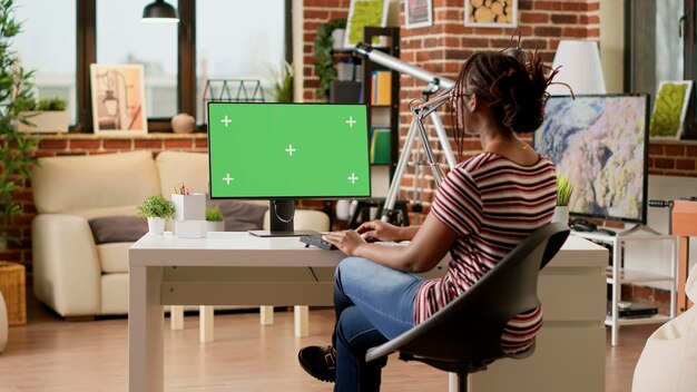 Empleado de la empresa usando pantalla verde en la computadora y haciendo trabajo remoto, mirando el monitor. Mujer de negocios que trabaja de forma remota con una plantilla de clave de croma aislada, fondo de maqueta en blanco.