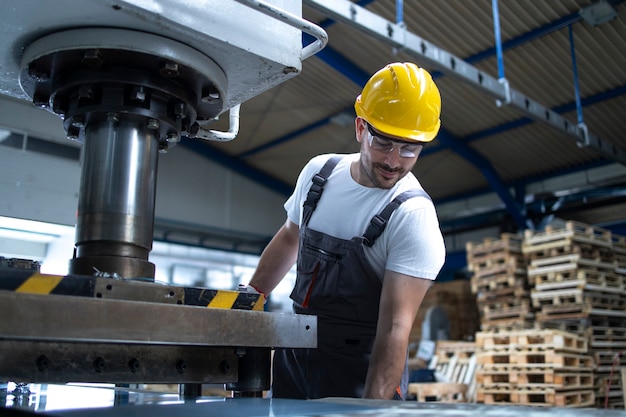 Empleado de fábrica que trabaja en la máquina de perforación industrial en la línea de producción