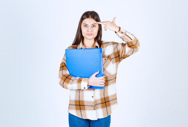 Empleado joven hermoso con carpeta azul apuntando a su cabeza.