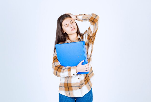 Empleado joven hermoso con la carpeta azul que tiene dolor de cabeza.