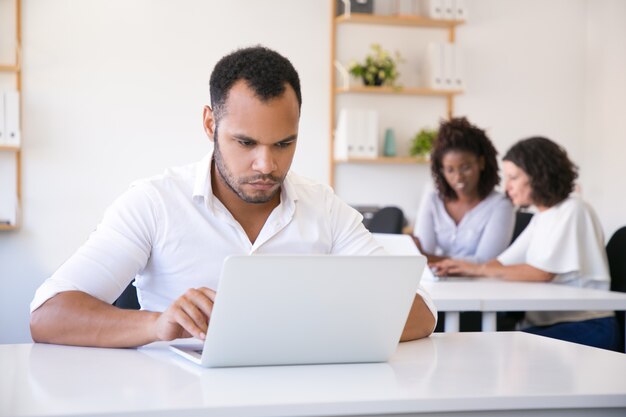 Empleado masculino enfocado usando laptop en la oficina