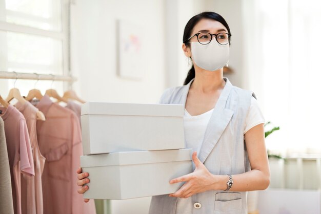 Empleado en la nueva máscara de uso normal llevando cajas de zapatos