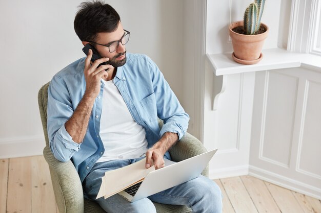 El empleado próspero y exitoso dirige el negocio, completa las ventas con el socio a través del teléfono celular, trabaja con una computadora portátil