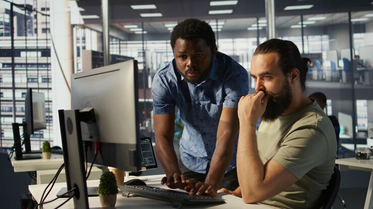 Foto gratuito empleado que utiliza una computadora para analizar conjuntos de datos asistido por un compañero de trabajo útil