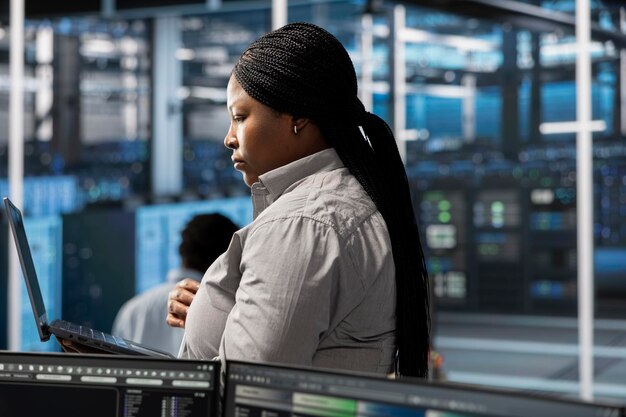 Empleado que utiliza una computadora portátil para supervisar las máquinas del centro de datos