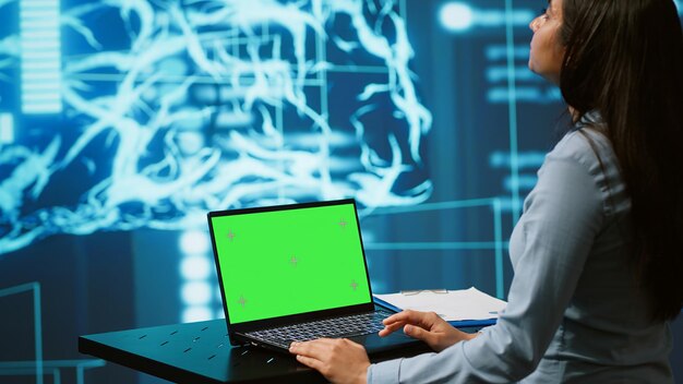 Empleado de una startup mirando gráficos usando software de IA en una computadora portátil de pantalla verde