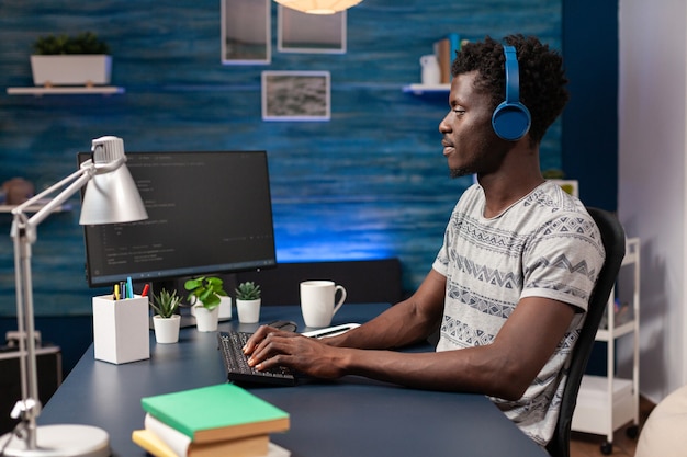 Empleado de ti afroamericano con auriculares trabajando de forma remota desde casa