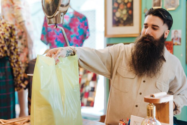 Empleado de la tienda amigable le da a un cliente su bolso en la tienda de ropa