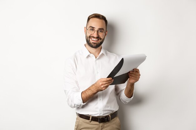 Empleador mirando satisfecho con CV, leyendo documento y sonriendo, de pie