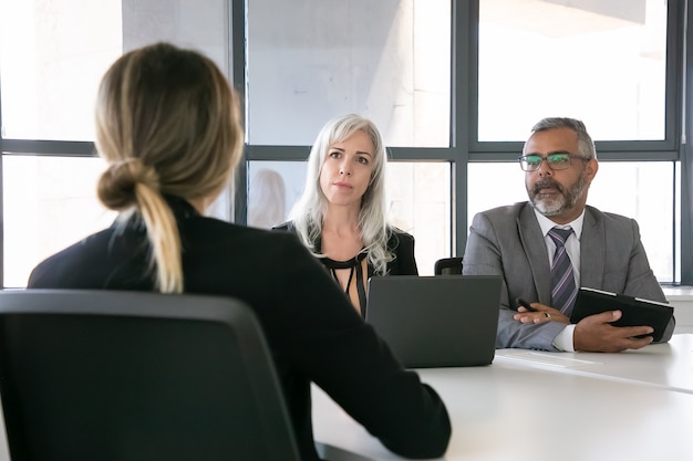 Empleador serio y gerente de recursos humanos hablando con el candidato de trabajo en la entrevista. Vista posterior, primer plano. Concepto de carrera y recursos humanos