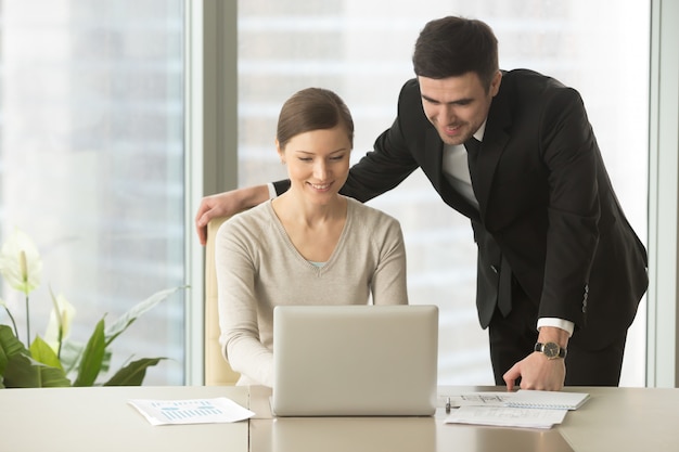 Empleados felices de la compañía que usan el ordenador portátil en la oficina