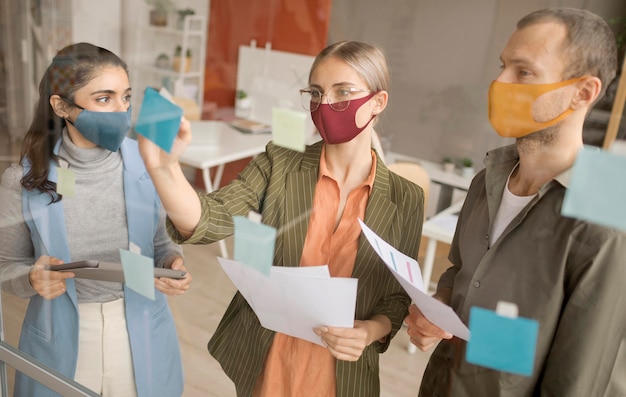 Foto gratuita empleados con máscaras faciales en la oficina.