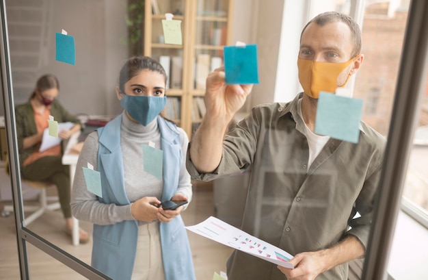 Foto gratuita empleados con máscaras faciales en la oficina.