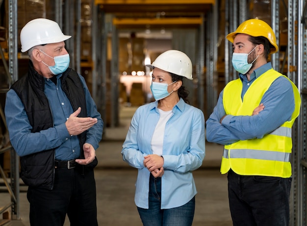 Foto gratuita empleados con máscaras trabajando en almacén