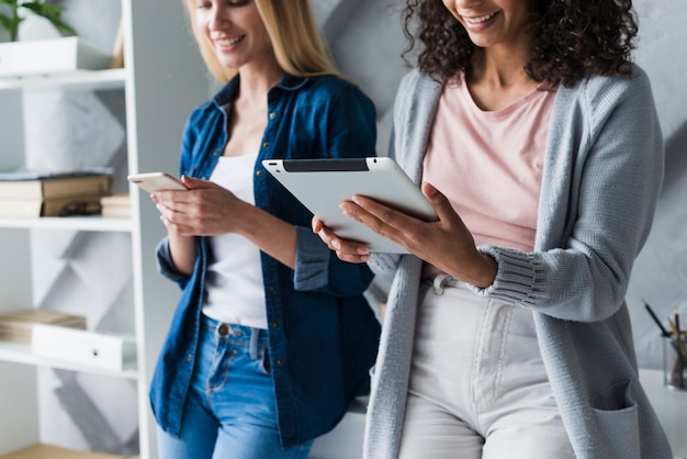 Empleados de oficina étnicos femeninos que usan gadgets