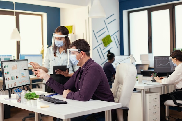 Empleados que trabajan juntos con mascarilla como medida de seguridad durante la covid19