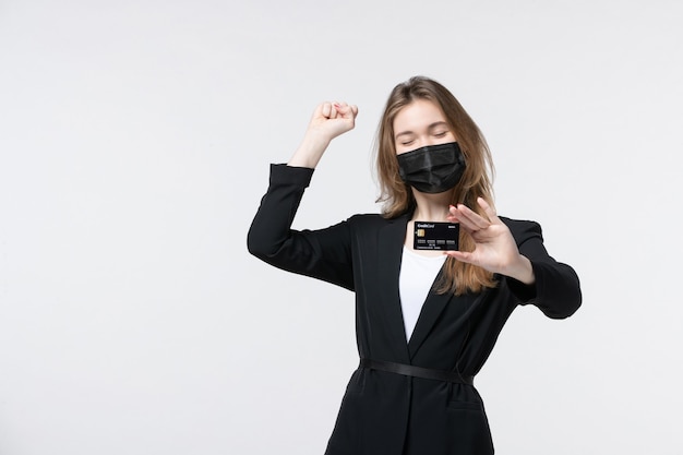 Emprendedora ambiciosa en traje con su máscara médica y mostrando la tarjeta bancaria en blanco