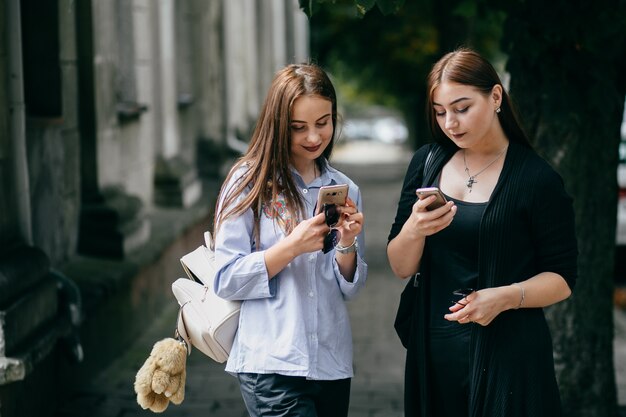 empresa de jóvenes amigos con teléfonos inteligentes caminando en la ciudad