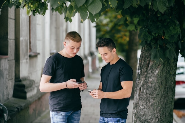 empresa de jóvenes amigos con teléfonos inteligentes caminando en la ciudad