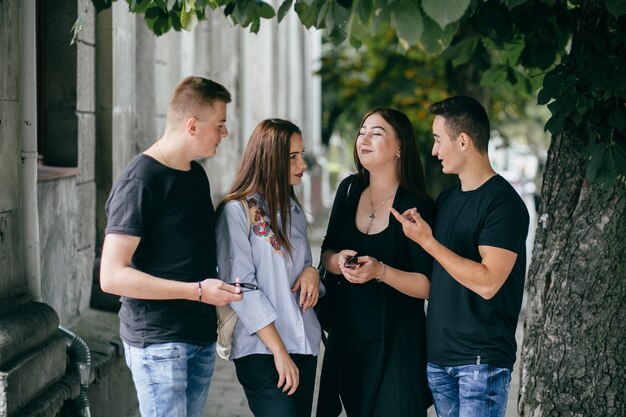 empresa de jóvenes amigos con teléfonos inteligentes caminando en la ciudad