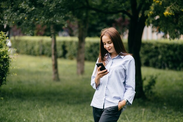 empresa de jóvenes amigos con teléfonos inteligentes caminando en la ciudad