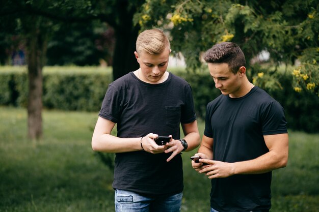 empresa de jóvenes amigos con teléfonos inteligentes caminando en la ciudad