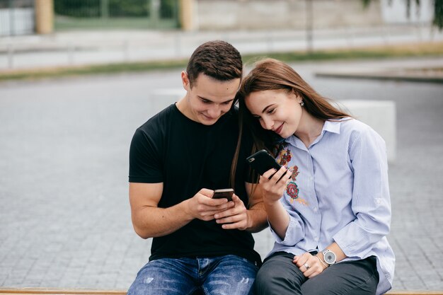 empresa de jóvenes amigos con teléfonos inteligentes caminando en la ciudad