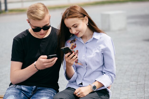 empresa de jóvenes amigos con teléfonos inteligentes caminando en la ciudad