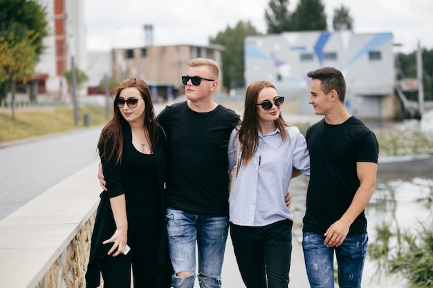 empresa de jóvenes amigos con teléfonos inteligentes caminando en la ciudad