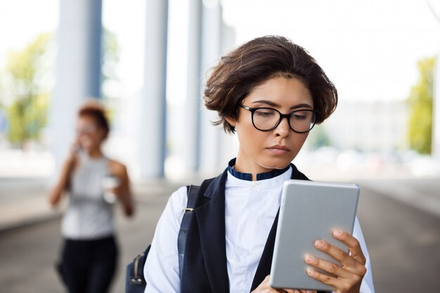 Empresaria acertada joven que mira la tableta sobre centro de negocios.