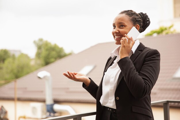 Empresaria afroamericana en traje de oficina sonriendo, parece segura y feliz, exitosa