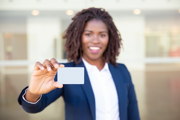 Empresaria alegre que sostiene la tarjeta en blanco